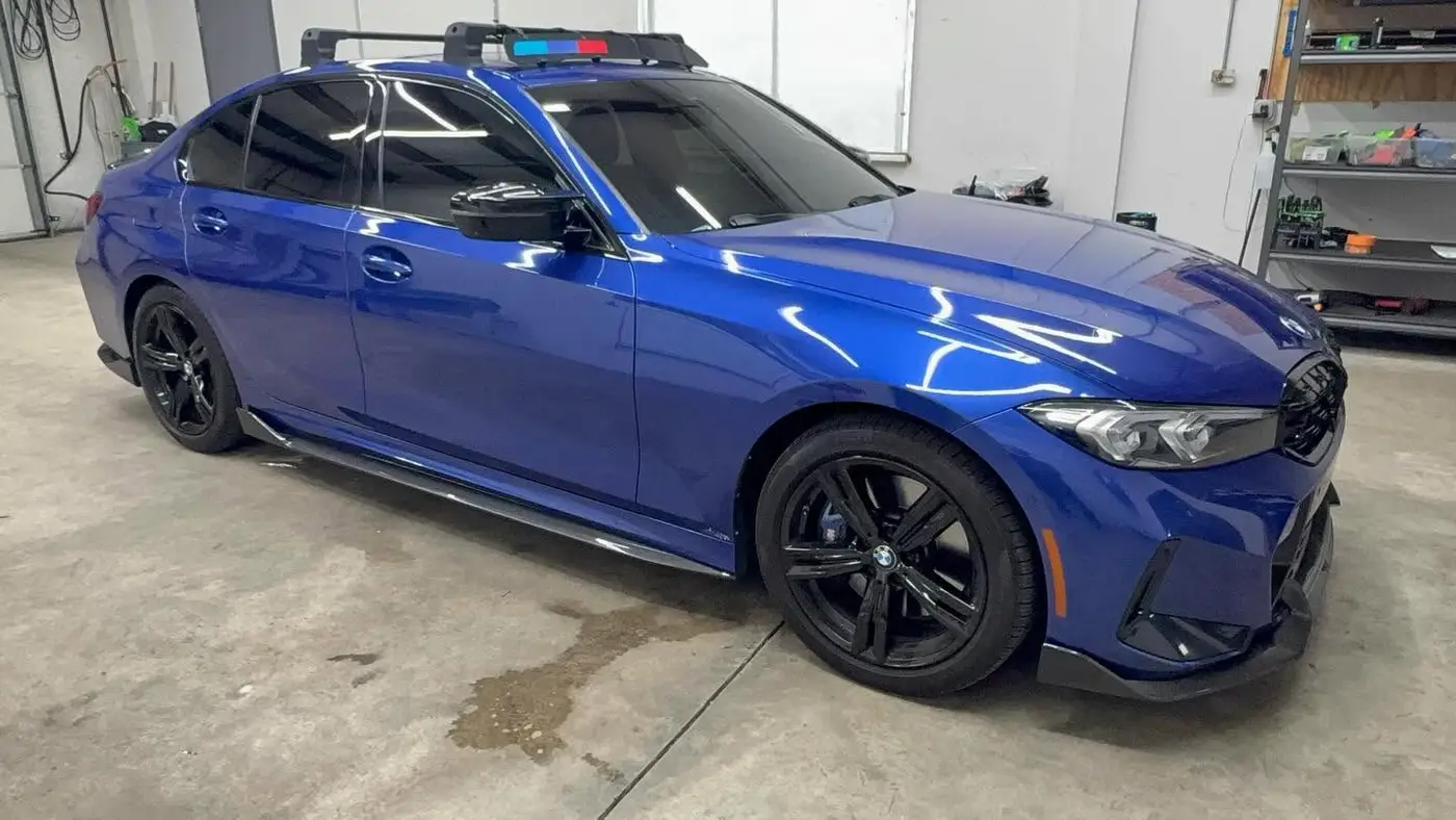 Blue BMW sedan with dark side window tint inside the shop