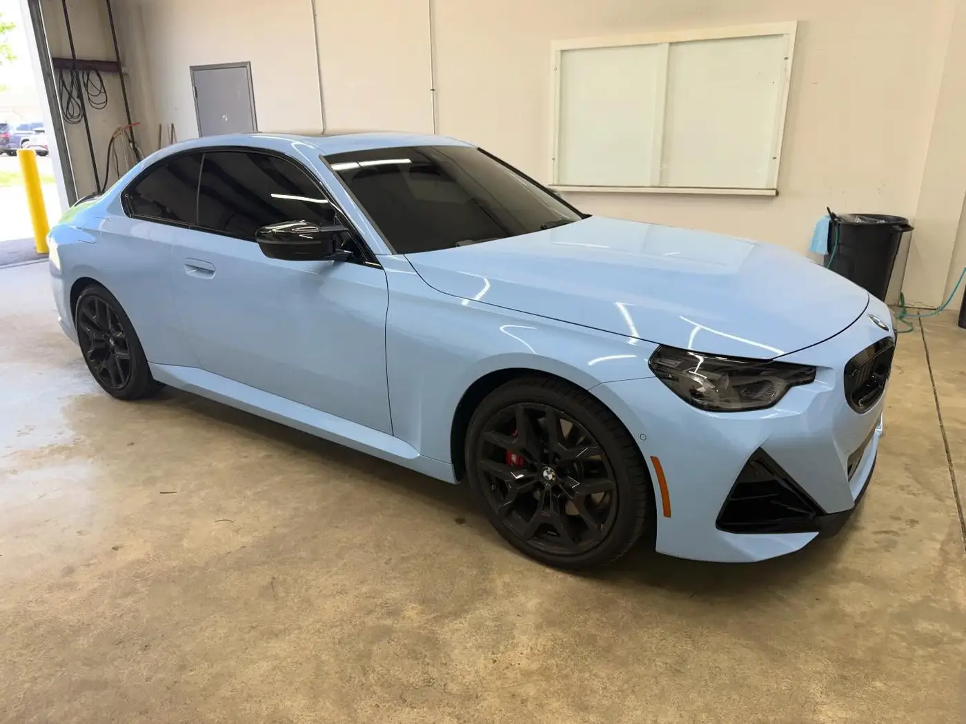 Light blue BMW coupe with dark window tint inside the bay